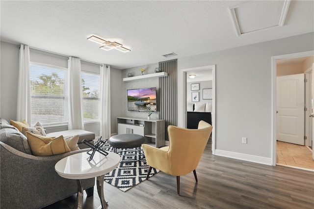living room with visible vents, a textured ceiling, baseboards, and wood finished floors