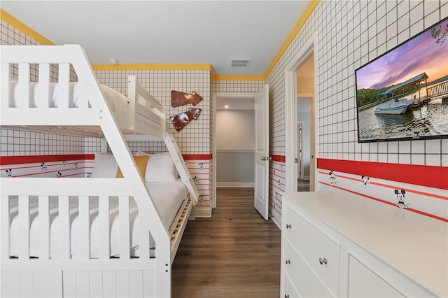 bedroom with visible vents, baseboards, wood finished floors, and wallpapered walls