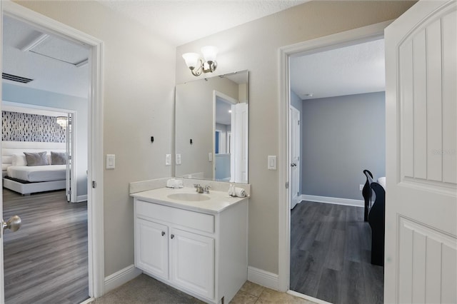 bathroom featuring vanity, baseboards, an inviting chandelier, visible vents, and wood finished floors