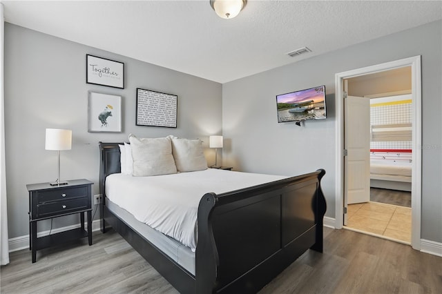 bedroom featuring wood finished floors, baseboards, and visible vents