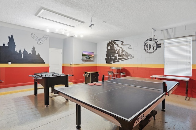 game room featuring a textured ceiling and concrete floors