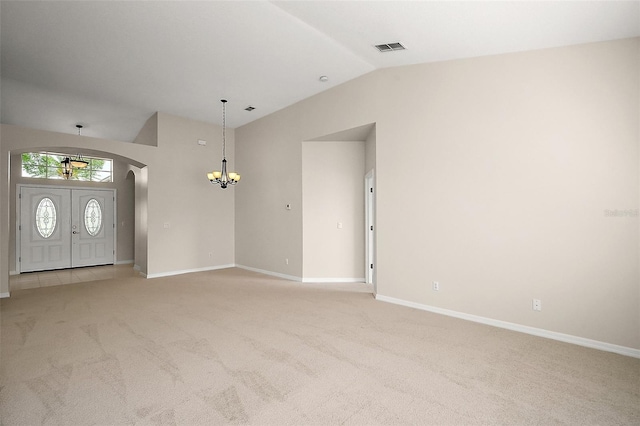 entrance foyer with a chandelier, arched walkways, light carpet, and lofted ceiling