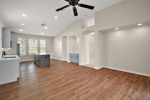 unfurnished living room featuring a sink, visible vents, recessed lighting, and arched walkways