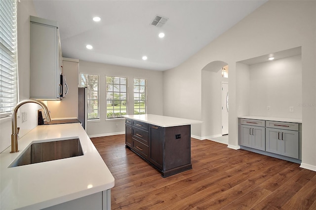 kitchen with a sink, stainless steel microwave, arched walkways, and dark wood-style flooring