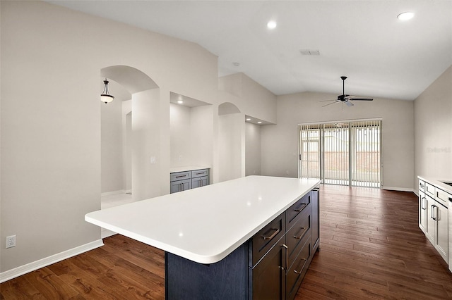 kitchen featuring arched walkways, light countertops, a ceiling fan, dark wood finished floors, and lofted ceiling
