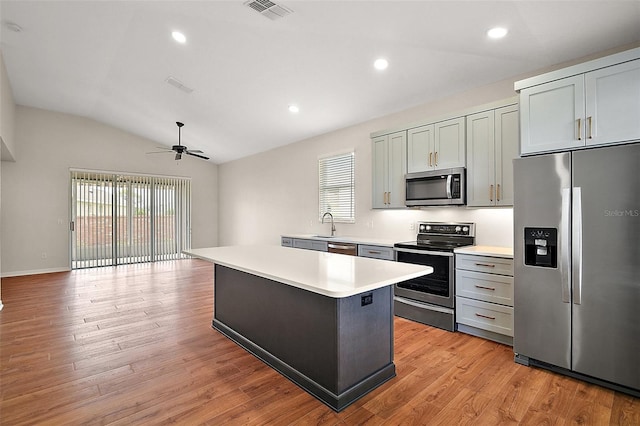 kitchen with ceiling fan, a kitchen island, appliances with stainless steel finishes, light countertops, and lofted ceiling