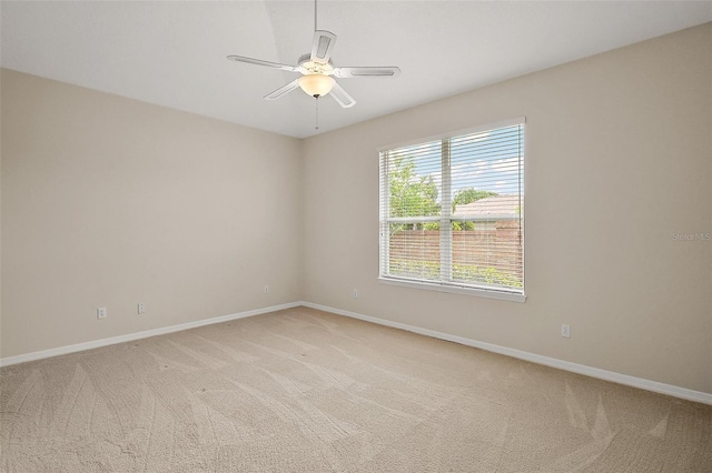 empty room with baseboards, ceiling fan, and light colored carpet