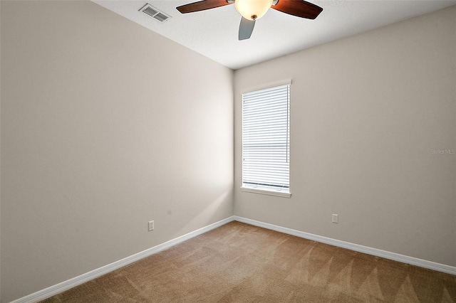 spare room with light carpet, visible vents, baseboards, and ceiling fan