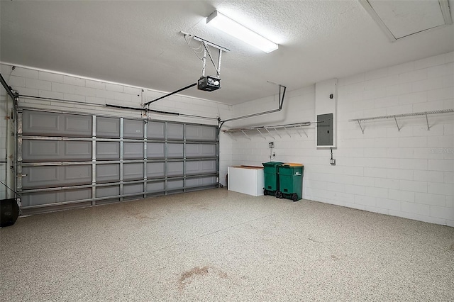 garage with a garage door opener, electric panel, and concrete block wall