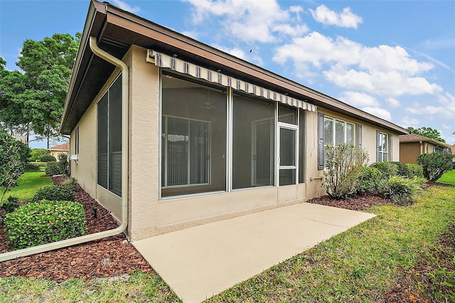 view of property exterior featuring a yard, stucco siding, and a sunroom