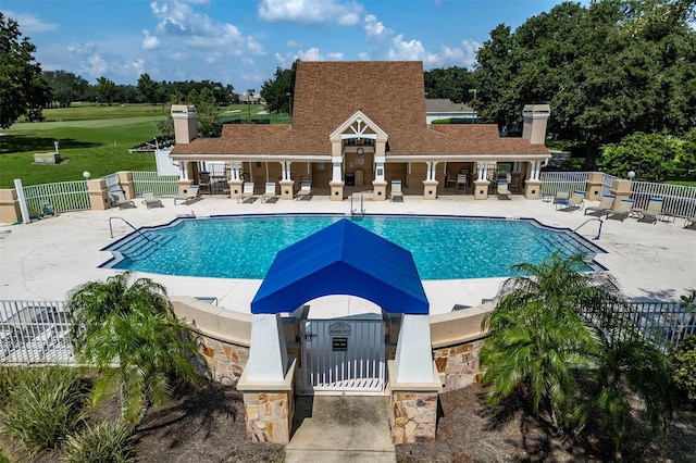 community pool with a patio area and fence
