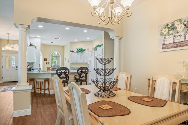 dining area with arched walkways, wood finished floors, ornate columns, a notable chandelier, and recessed lighting