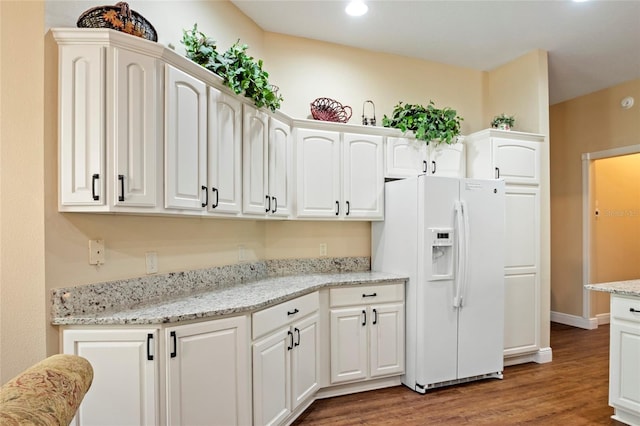 kitchen with light stone countertops, white fridge with ice dispenser, white cabinetry, recessed lighting, and light wood-type flooring