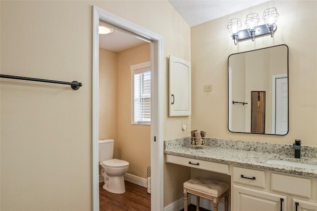 bathroom with vanity, baseboards, toilet, and wood finished floors