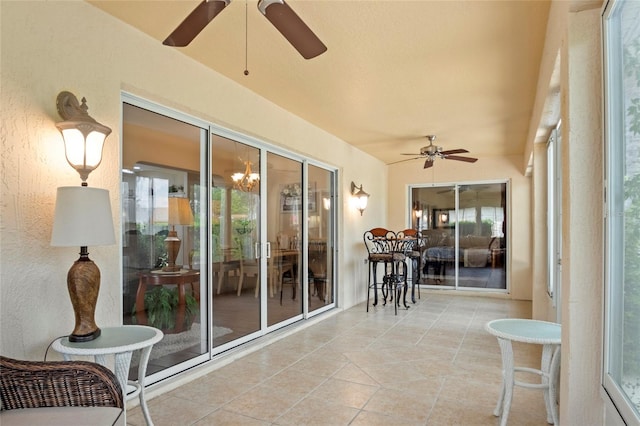 sunroom / solarium with a textured wall, ceiling fan, and tile patterned floors