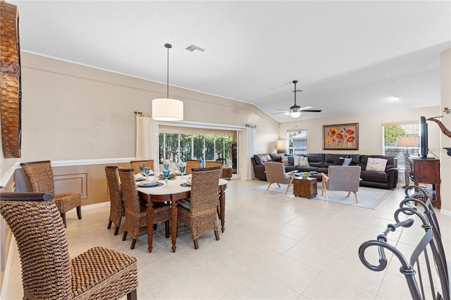 dining space featuring visible vents, a ceiling fan, vaulted ceiling, and light tile patterned floors