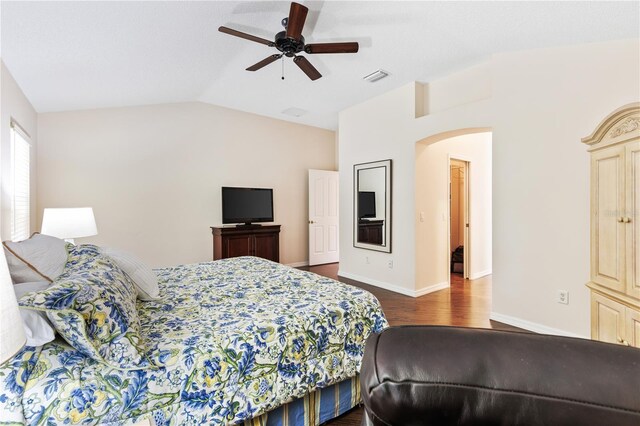 bedroom featuring baseboards, vaulted ceiling, dark wood-style floors, visible vents, and arched walkways