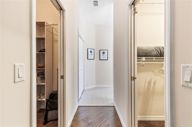 hallway with visible vents, baseboards, and wood finished floors