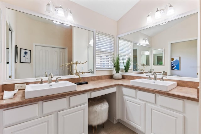 full bathroom with a sink, tile patterned floors, double vanity, and lofted ceiling