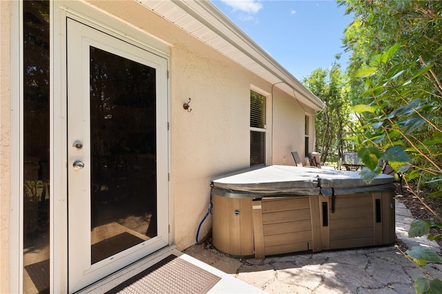 entrance to property featuring stucco siding and a hot tub