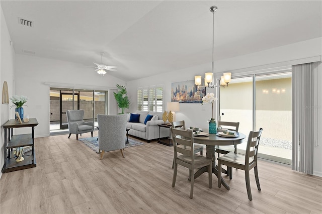 dining area with light wood-style flooring, ceiling fan with notable chandelier, visible vents, and lofted ceiling