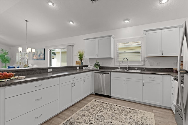 kitchen with a sink, appliances with stainless steel finishes, dark countertops, and a healthy amount of sunlight