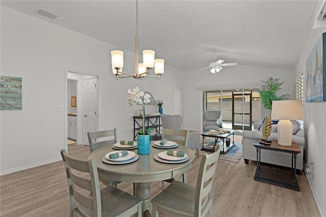 dining space with visible vents, ceiling fan with notable chandelier, vaulted ceiling, and light wood-style flooring