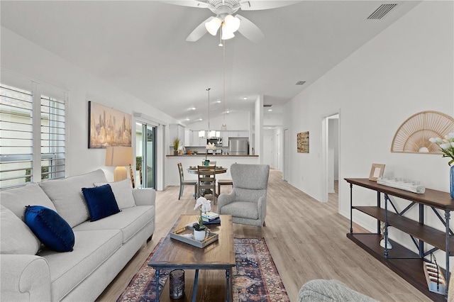 living area featuring visible vents, light wood-type flooring, vaulted ceiling, and ceiling fan