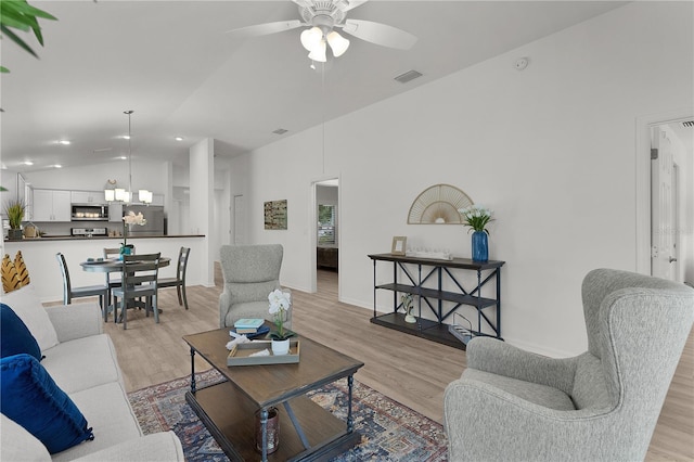 living room with visible vents, light wood-type flooring, recessed lighting, ceiling fan with notable chandelier, and high vaulted ceiling