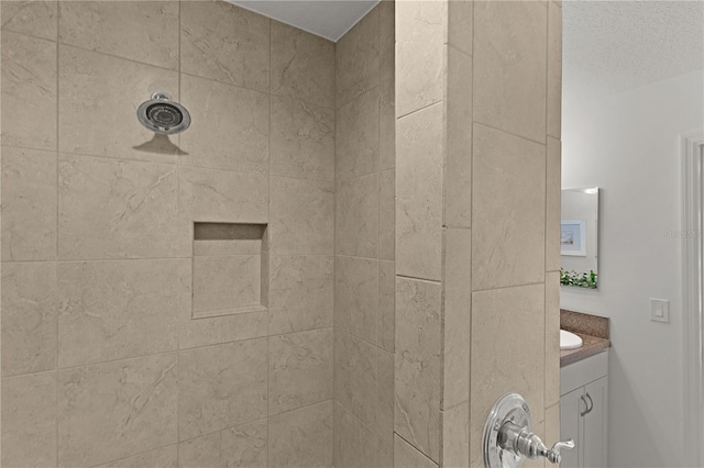 bathroom with tiled shower and vanity