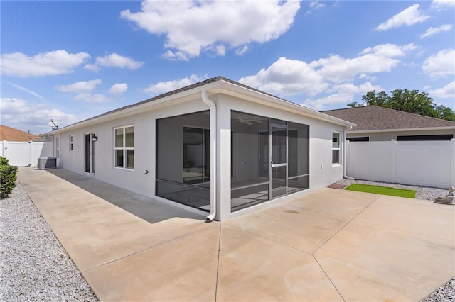 back of property with a sunroom, fence, a patio, stucco siding, and a gate
