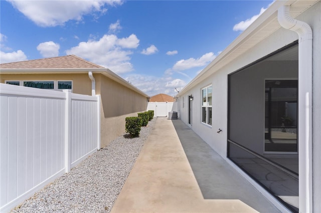 view of property exterior with roof with shingles, stucco siding, cooling unit, and fence