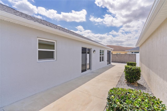 view of home's exterior with fence, a patio, and stucco siding