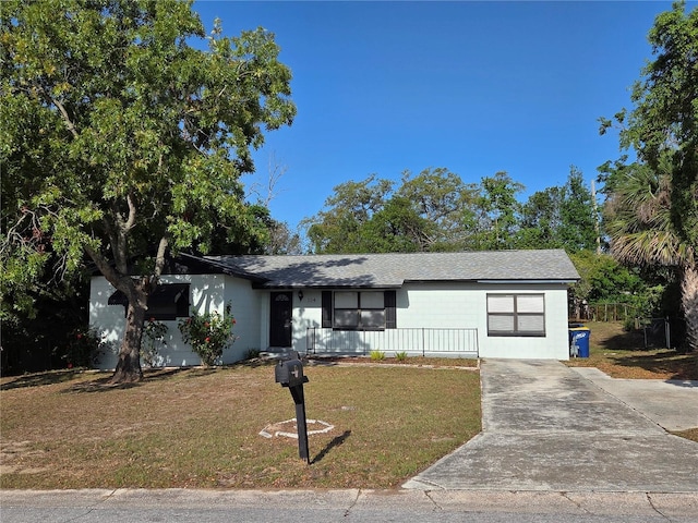 ranch-style house featuring a porch, roof with shingles, concrete driveway, and a front yard