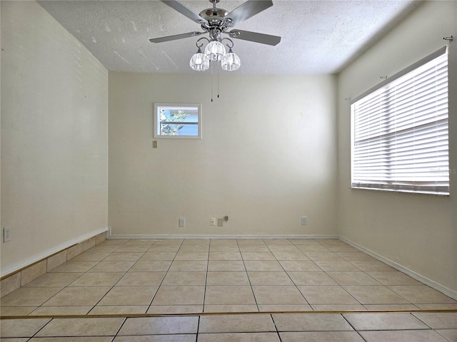 empty room with a textured ceiling, light tile patterned floors, and a ceiling fan