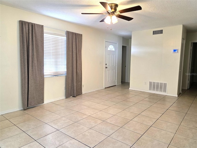 spare room with visible vents, ceiling fan, light tile patterned floors, and a textured ceiling