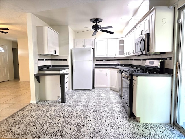 kitchen with backsplash, dark countertops, white cabinets, ceiling fan, and stainless steel appliances
