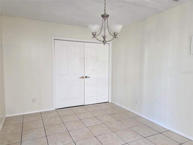 unfurnished dining area featuring an inviting chandelier, baseboards, and light tile patterned floors
