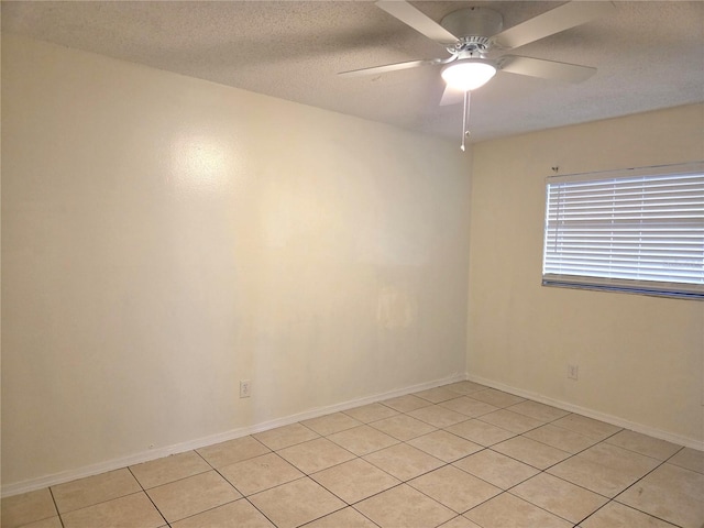 empty room with light tile patterned floors, baseboards, and a ceiling fan
