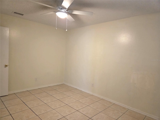 empty room featuring visible vents, a ceiling fan, light tile patterned floors, and a textured ceiling