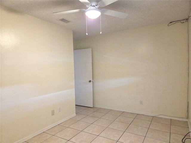 spare room featuring baseboards, light tile patterned floors, a textured ceiling, a ceiling fan, and visible vents
