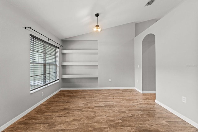 17 Eugenia Ct N, Homosassa, FL 34446 - spare room with built in features, baseboards, arched walkways, wood finished floors, and vaulted ceiling