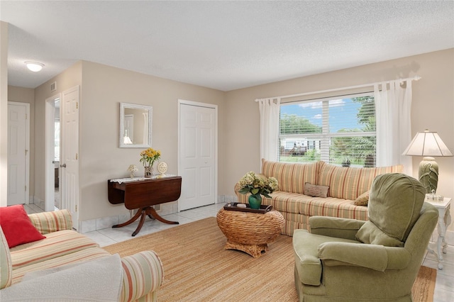 living area featuring a textured ceiling, light tile patterned floors, and visible vents