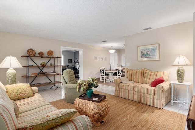 tiled living room featuring visible vents and a textured ceiling