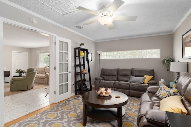 living room with light wood-style flooring, a textured ceiling, a ceiling fan, and visible vents