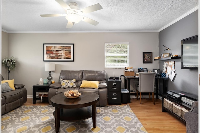 living room with ornamental molding, light wood-style flooring, a ceiling fan, and a textured ceiling