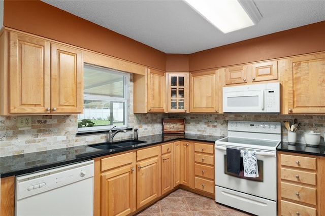 kitchen with tasteful backsplash, white appliances, glass insert cabinets, light tile patterned floors, and a sink