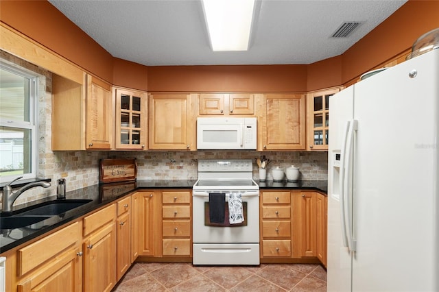 kitchen featuring tasteful backsplash, visible vents, glass insert cabinets, a sink, and white appliances
