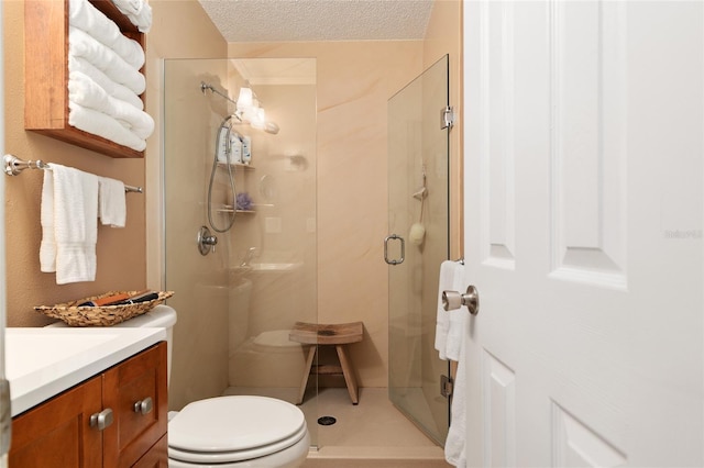 full bath featuring toilet, a stall shower, vanity, and a textured ceiling