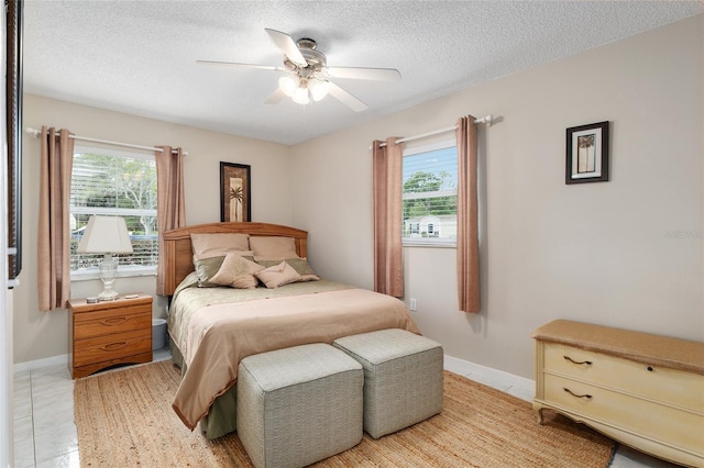 bedroom featuring a textured ceiling, ceiling fan, baseboards, and multiple windows
